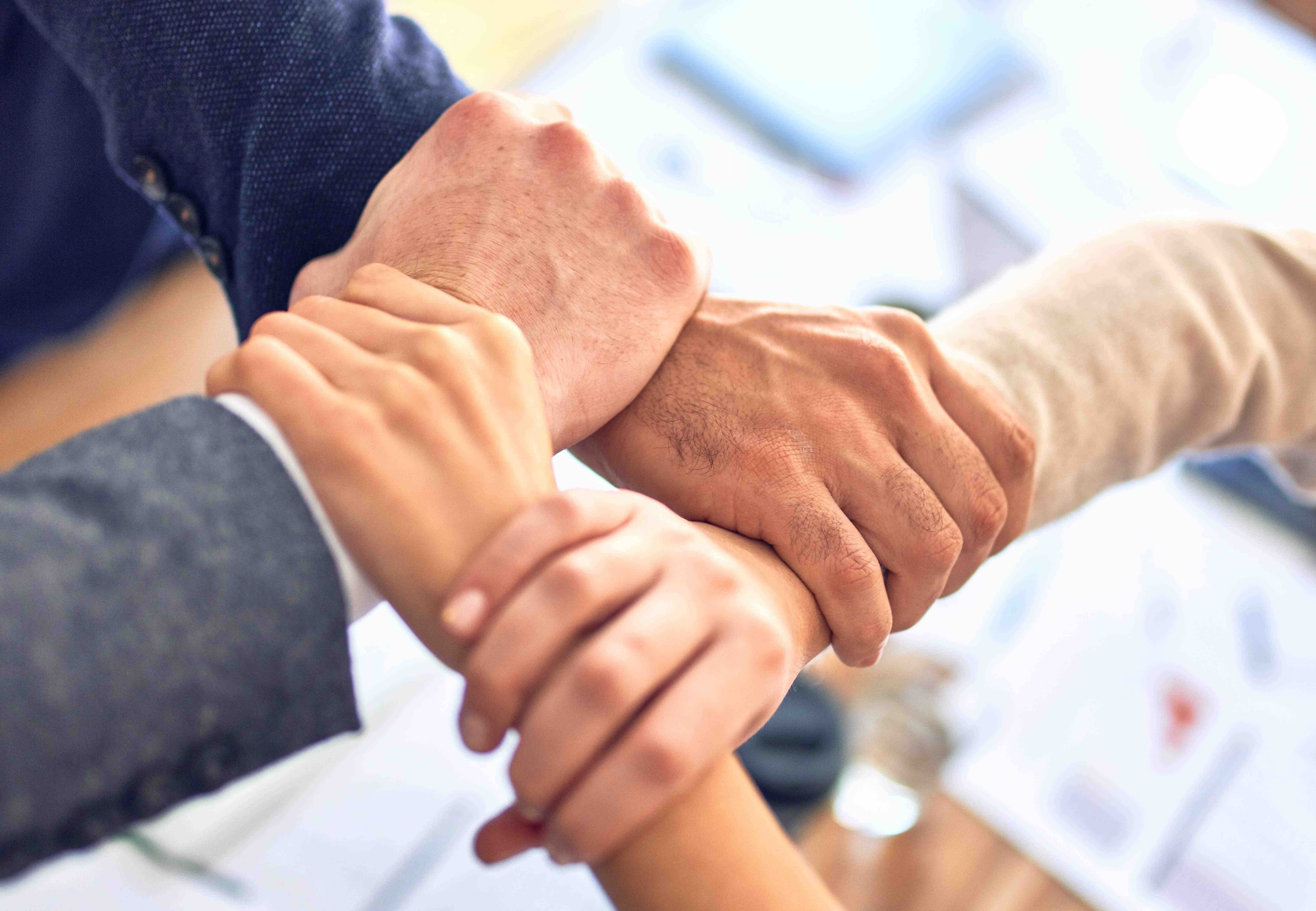Menschen legen ihre Hände zusammen als Zeichen der Zusammenarbeit